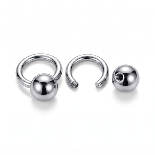A polished silver-toned metal Piercing ring shown in three views: assembled, open, and with the ball end separated. The metal has a highly reflective, polished finish on a clean white background.